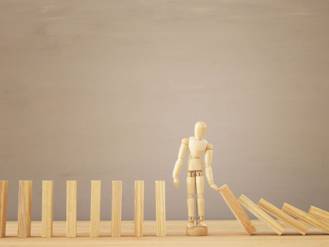 A wooden dummy stopping the domino effect. retro style image executive and risk control concept. (Demo)