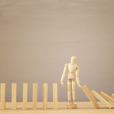 A wooden dummy stopping the domino effect. retro style image executive and risk control concept. (Demo)